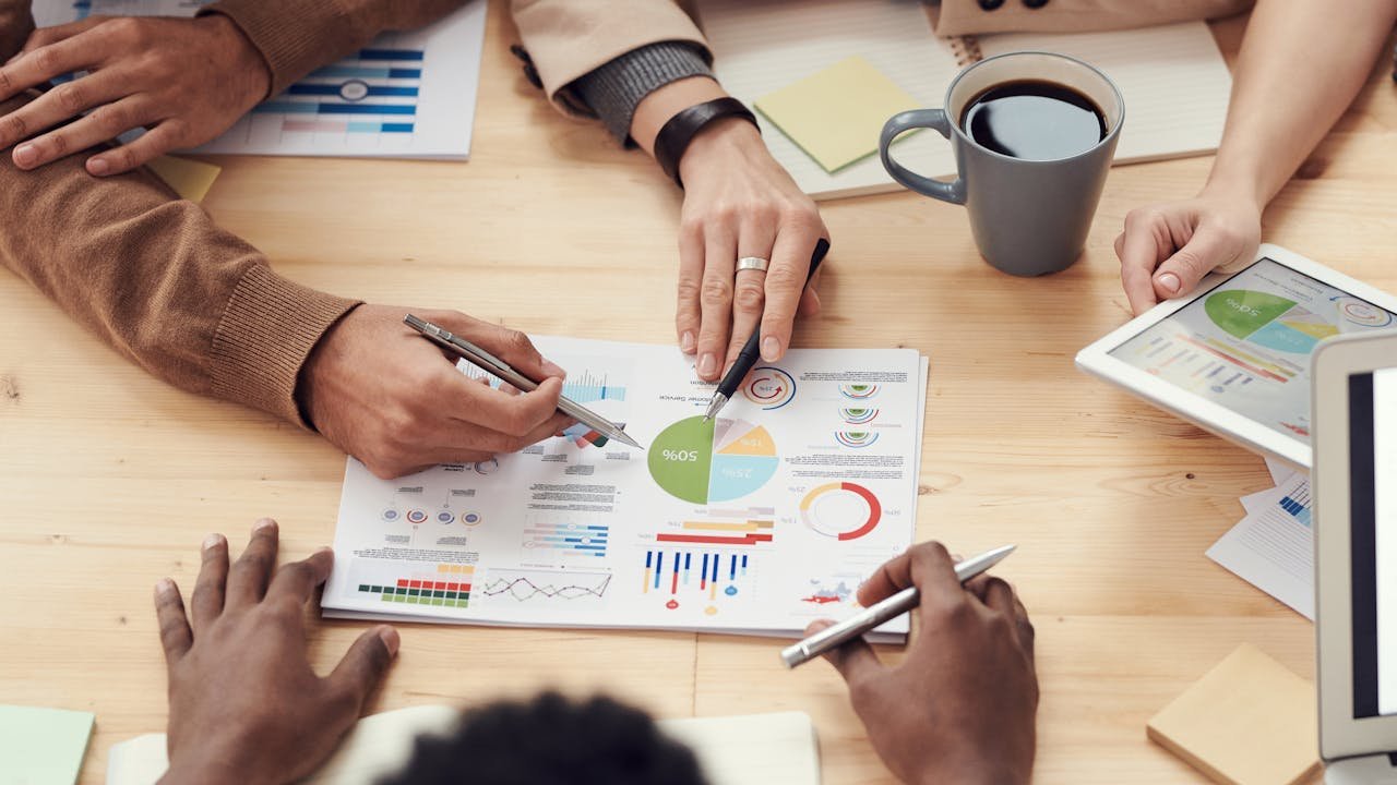 Business team in meeting room analyzing workflow diagrams on whiteboard with sticky notes showing content production stages and accessibility checkpoints