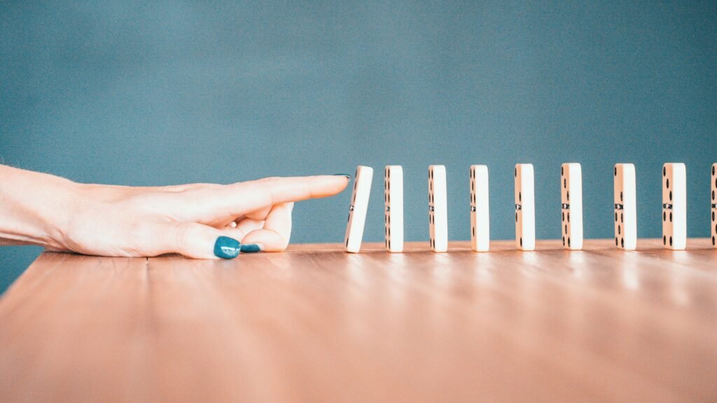 Close-up shot of white dominoes falling in a chain reaction, illustrating the cascading negative consequences of missing alt text in e-commerce, from lost SEO to legal risks